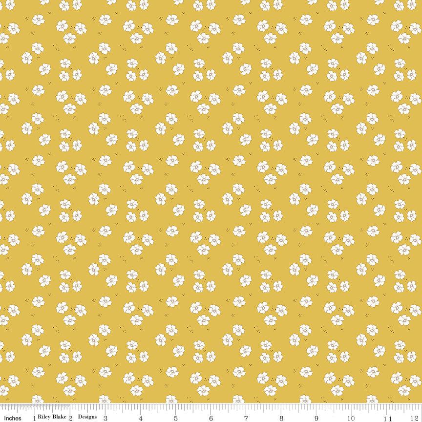 Yellow fabric with small white floral pattern and ruler for scale
