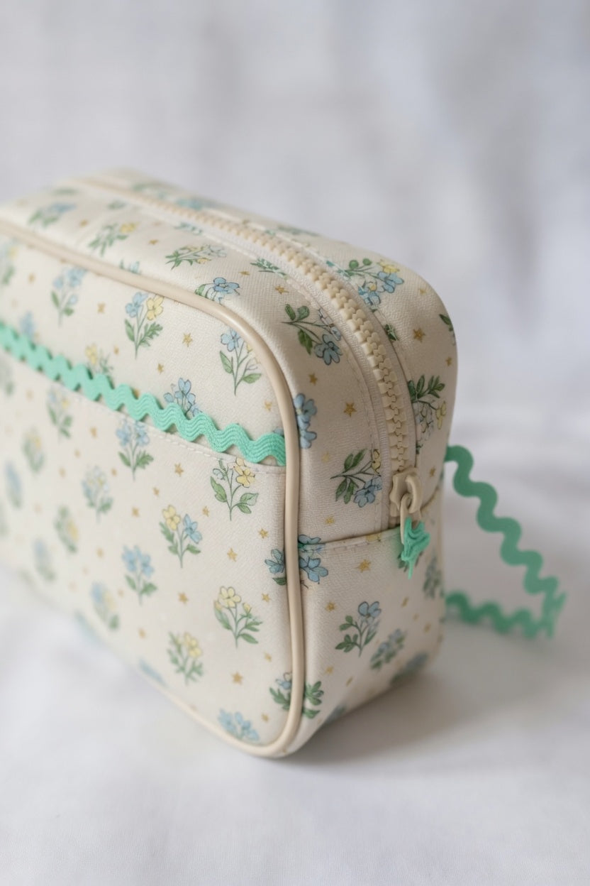 Floral-patterned pouch with a green zipper and mint baby ric rac on a white background