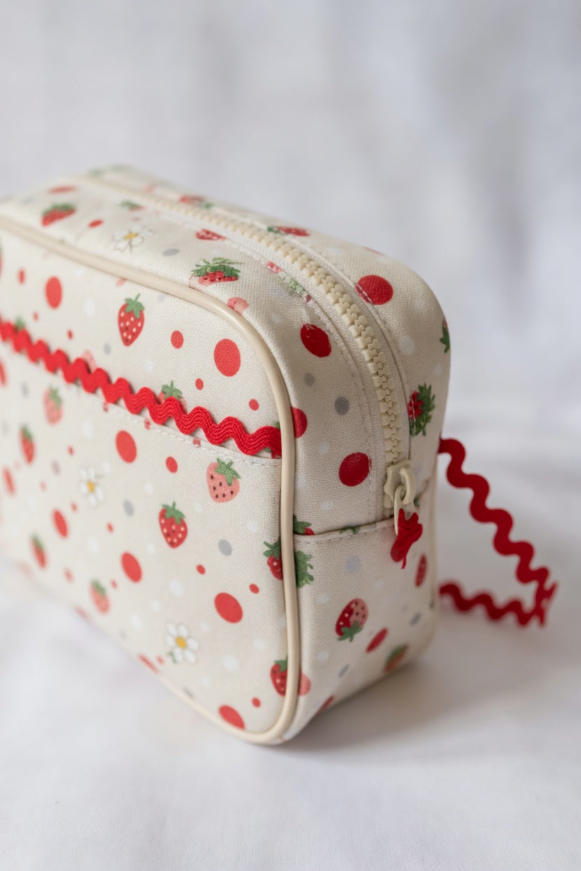 Small pouch with strawberry pattern and red baby ric rac on a white background