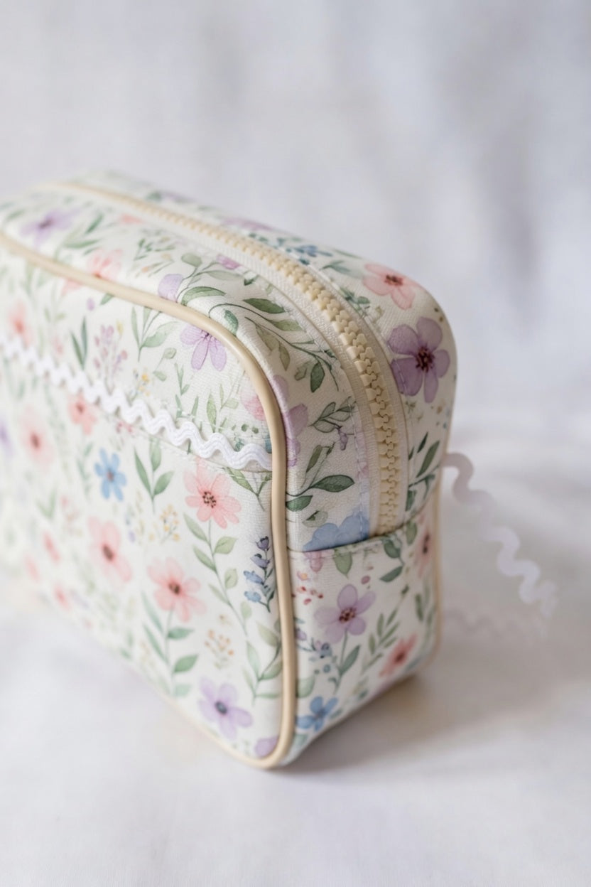 Floral-patterned toiletry bag with white baby ric rac on a white background